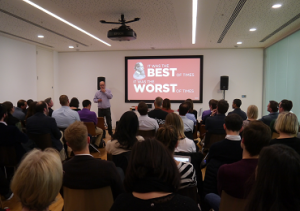 David Roth, CEO of The Store, gives his introduction to the Mindshare Future of Retail Huddle. He stands at the front of a room full of people, next to a projector screen which reads 'The best of times, the worst of times', a reference to Charles Dickens.