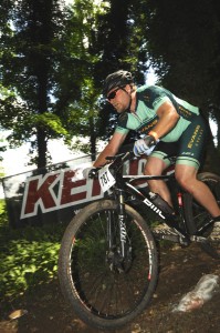 A picture of a serious cyclist in the middle of a bike ride, wearing a helmet and sunglasses with Evans Cycles-branded lycra. THe number 787 is attached to the front of his bike.