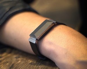 A photograph of a person's wrist wearing a black Altruis filtering bracelet.