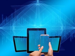 A picture of several different devices - tablets and a smartphone - in front of a blue background with binary streaming down from the top of the image. A hand in the foreground is holding the smartphone and tapping the screen with one finger.