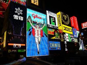 A photograph of various brightly-coloured billboards at night in Japan.