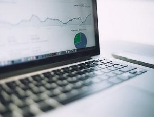 A stock photograph of a laptop, showing charts from Google Analytics on its screen.
